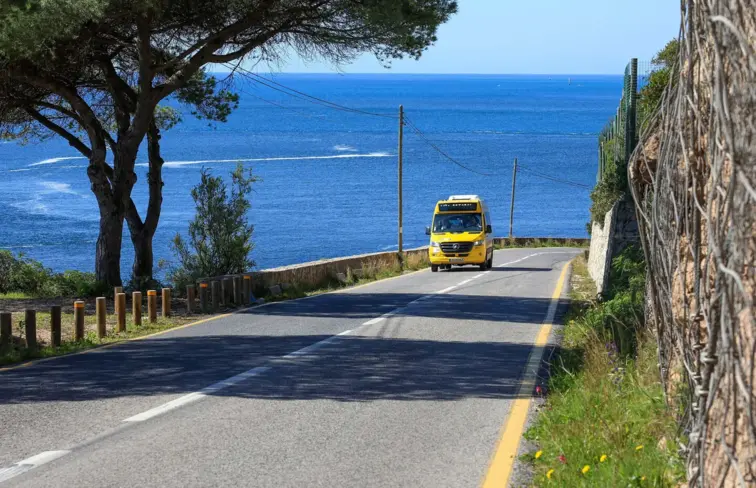 Estrada com autocarro, ao fundo mar.